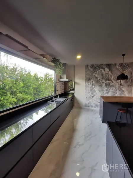 Townhouse for rent in Bang Phli, Samut Prakan - Kitchen walkway toward feature marble wall and island with pendant lighting.