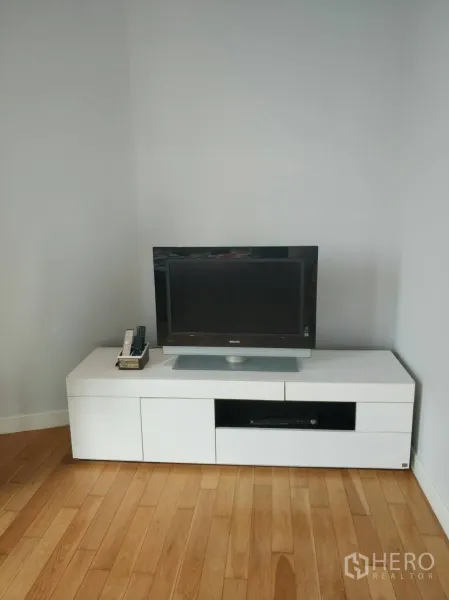 คอนโด ให้เช่าหรือขายในKhlong Toei, Bangkok - มุมห้องนั่งเล่นมีทีวีจอแบนบนตู้วางสีขาว พื้นไม้โทนอุ่น