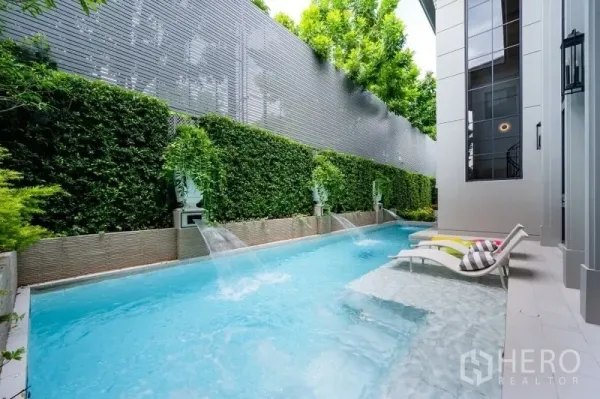 บ้าน ขายในBang Kapi, Bangkok - สระว่ายน้ำส่วนตัวทรงยาว มีน้ำตกตกแต่ง กำแพงต้นไม้สูง และเตียงอาบแดด