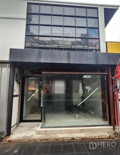 零售空间 出租在Khlong Toei, Bangkok - 临街店面，双层挑高网格玻璃与推拉门，内部空置可见。