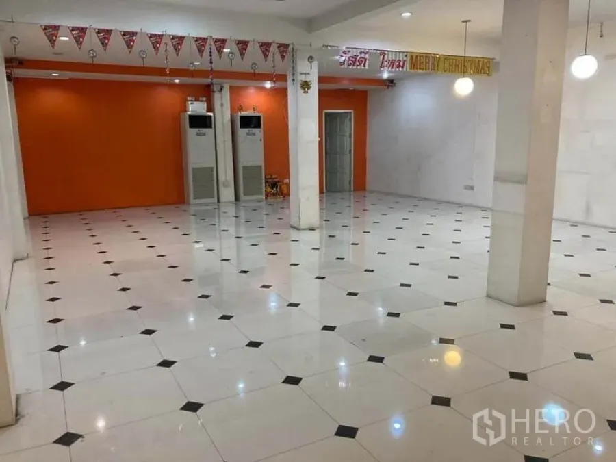 店屋 出租在Suan Luang, Bangkok - 大型零售大厅，橙色特色墙、立柱、天花灯和柜式空调。