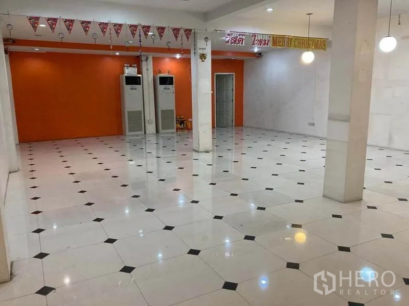 店屋 出租在Suan Luang, Bangkok - 大型零售大厅，橙色特色墙、立柱、天花灯和柜式空调。