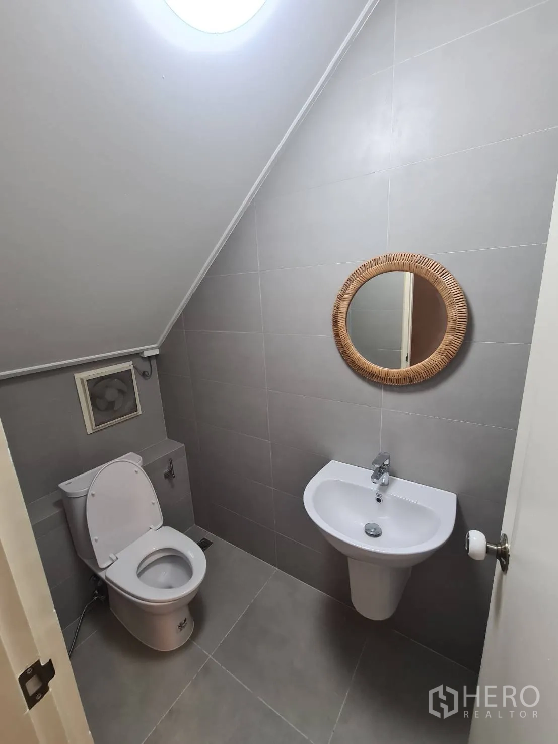 บ้าน ให้เช่าในKhlong Toei, Bangkok - ห้องน้ำสำหรับแขกขนาดกะทัดรัด ผนังกระเบื้องสีเทา กระจกกลม และสกายไลต์