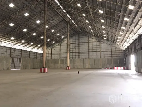 货栈 出租在Phra Nakhon Si Ayutthaya - 高挑仓库内部，钢桁架屋顶与采光板，光滑混凝土地面