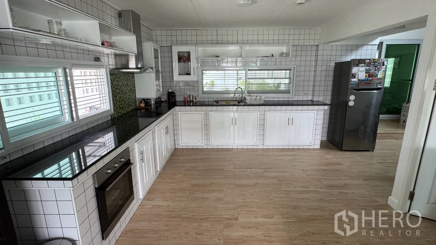 Detached House for rent in Saphan Sung, Bangkok - Long kitchen counter with built-in oven, hood, open shelves, and windows.