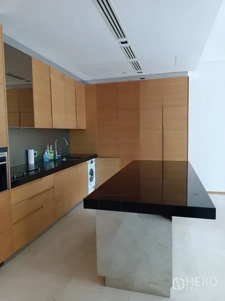 公寓 出租或出售在Bang Rak, Bangkok - 现代厨房，黑色石材中岛、木质橱柜与嵌入式电器。