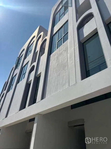 Townhouse for sale - Angled view of minimalist townhouse façade with vertical slat detailing and large glass windows above the carport.