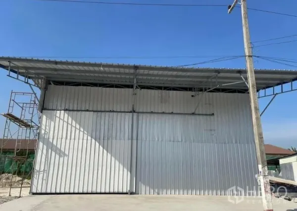 Warehouse for rent in Min Buri, Bangkok - Front exterior of metal-clad warehouse with wide sliding doors and driveway in Min Buri, Bangkok.