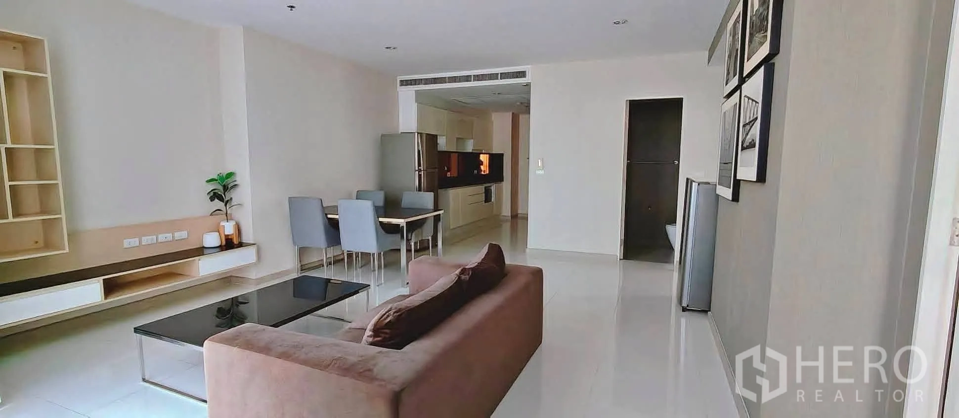 Condominium for rent in Watthana, Bangkok - Open-plan living room with sofa, glass coffee table, dining set for four, and built-in TV console.