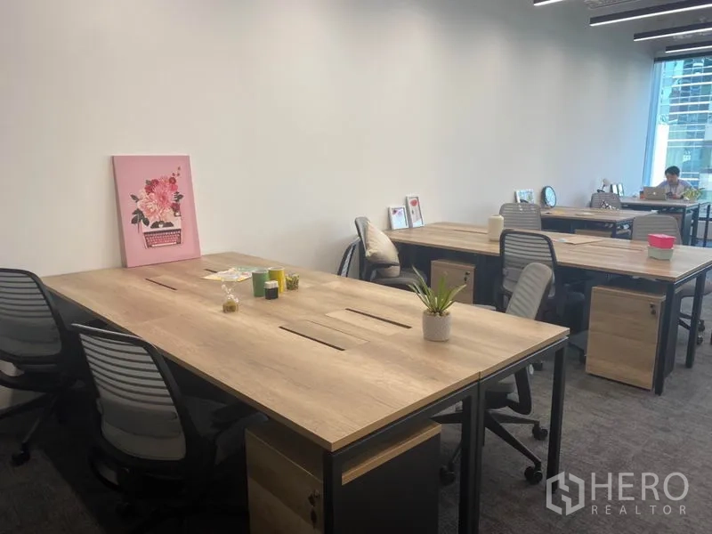 办公空间 出租在Pathum Wan, Bangkok - 明亮工位区，木质桌面与办公椅，简洁白墙背景。