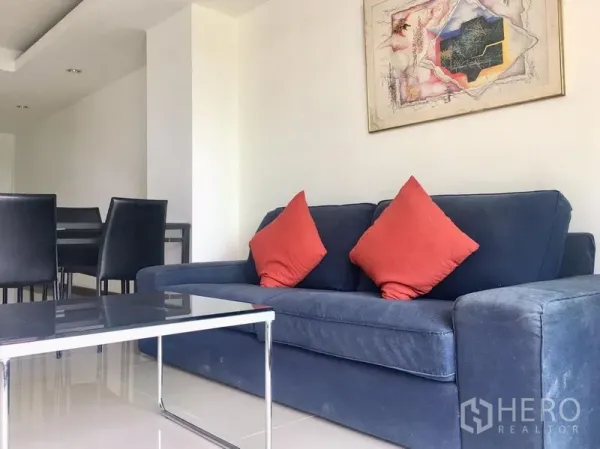 คอนโด ให้เช่าในKhlong Toei, Bangkok - โซฟาสีน้ำเงินพร้อมหมอนอิงสีแดง โต๊ะกลางกระจก และชุดโต๊ะทานอาหาร