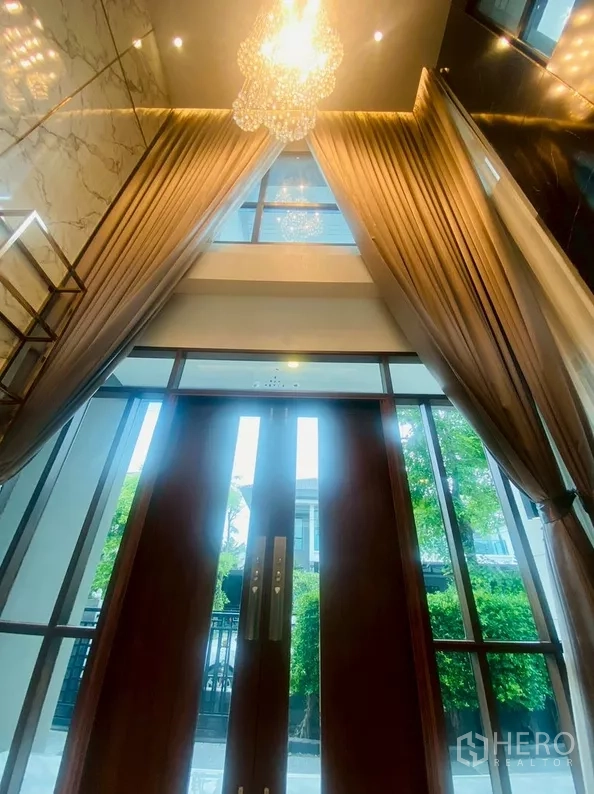 บ้าน ให้เช่าในPrawet, Bangkok - โถงทางเข้าเพดานสูงพร้อมโคมระย้า ผ้าม่านทิ้งตัวยาว และประตูกระจกบานใหญ่