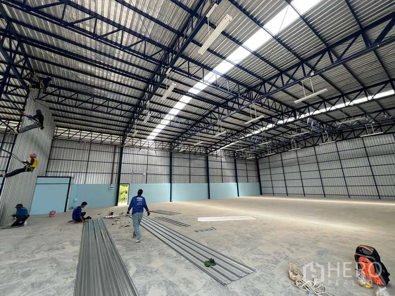 Warehouse for rent in Lat Krabang, Bangkok - Large column-free warehouse hall with high roof, metal panels and ample lighting with materials on the floor.