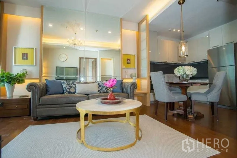Condominium for rent in Watthana, Bangkok - Open-plan living and dining area with modern kitchen, round coffee table and pendant light.
