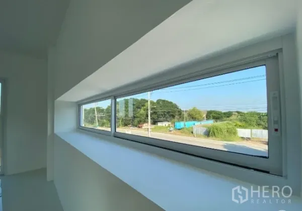 Warehouse for sale in Sai Noi, Nonthaburi - Long horizontal window in the upstairs office overlooking the road and green surroundings.