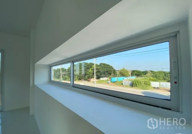Warehouse for sale in Sai Noi, Nonthaburi - Long horizontal window in the upstairs office overlooking the road and green surroundings.