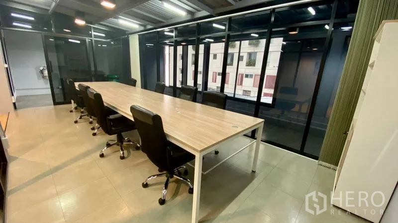 办公空间 出租在Sathon, Bangkok - 落地窗旁的长会议桌与高背椅，可眺望城市建筑景观。