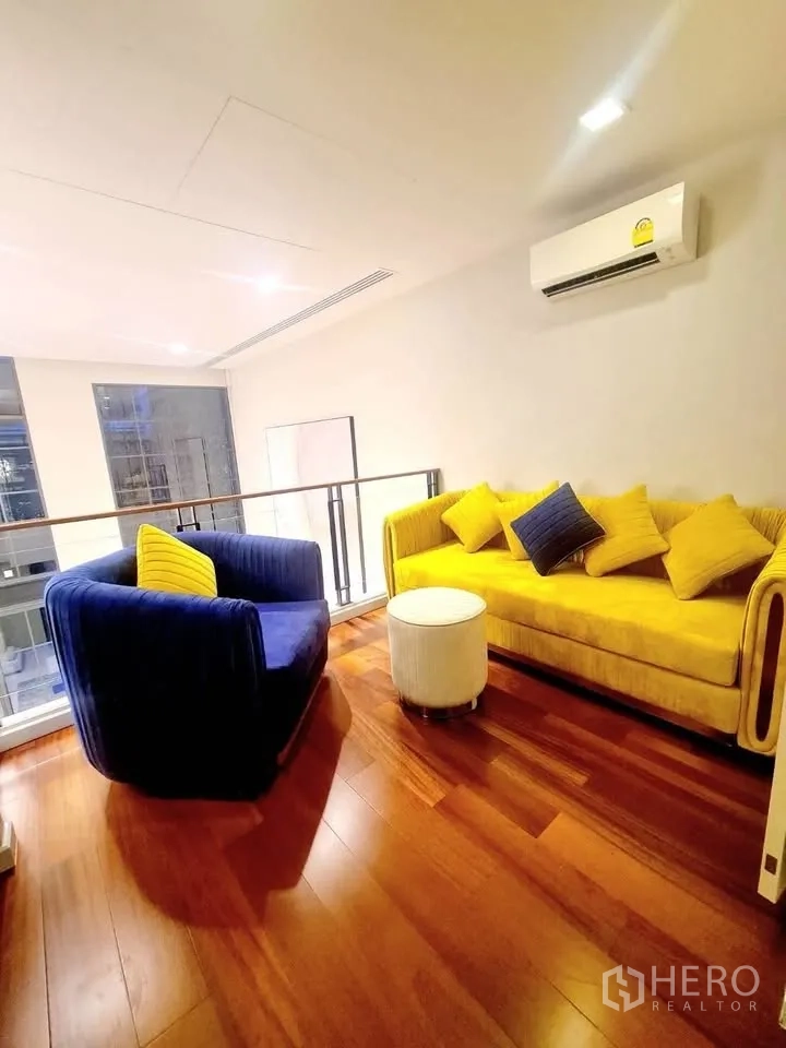 Townhouse for rent or sale in Watthana, Bangkok - Mezzanine lounge with colorful sofas on polished wooden flooring.