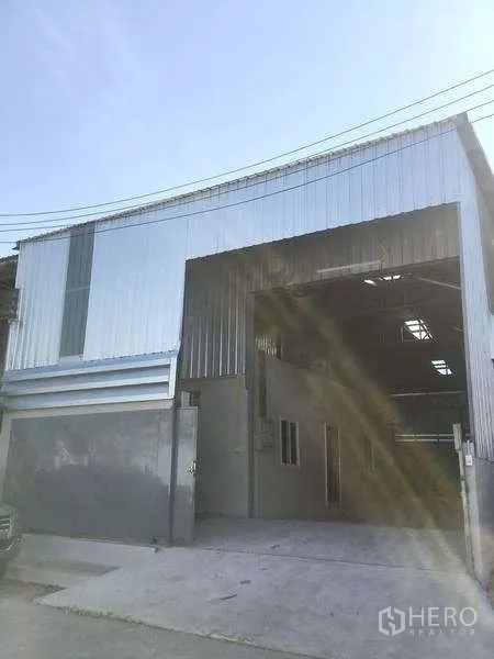Warehouse for rent in Mueang Samut Prakan, Samut Prakan - Front view of warehouse facade with tall entry and driveway.