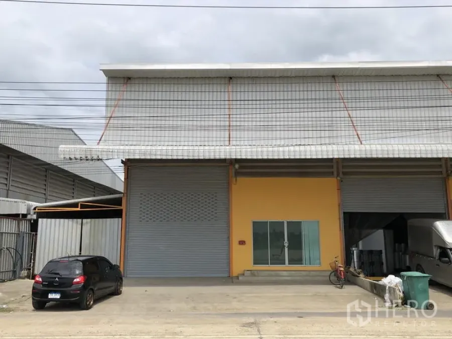 Warehouse for rent in Lat Lum Kaeo, Pathum Thani - Front view of a modern warehouse with twin roller shutters, glass office entry and wide driveway parking.