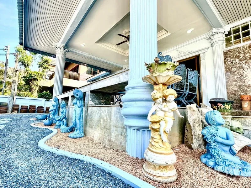 บ้าน ให้เช่าในTaling Chan, Bangkok - ภาพระยะใกล้ของเสาชานระเบียงคลุมหลังคา พร้อมประติมากรรมแต่งสวนข้างทางกรวด.