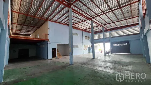 Factory for rent in Pak Kret, Nonthaburi - Open production space with mezzanine, red steel beams and roller shutter access
