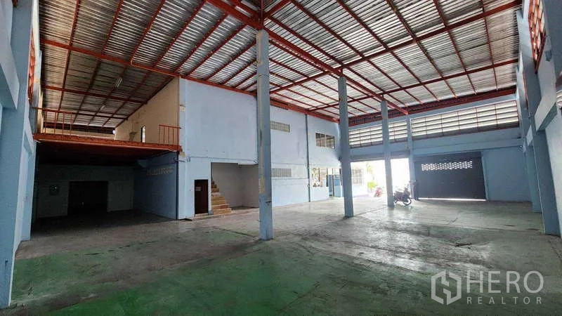 Factory for rent in Pak Kret, Nonthaburi - Open production space with mezzanine, red steel beams and roller shutter access