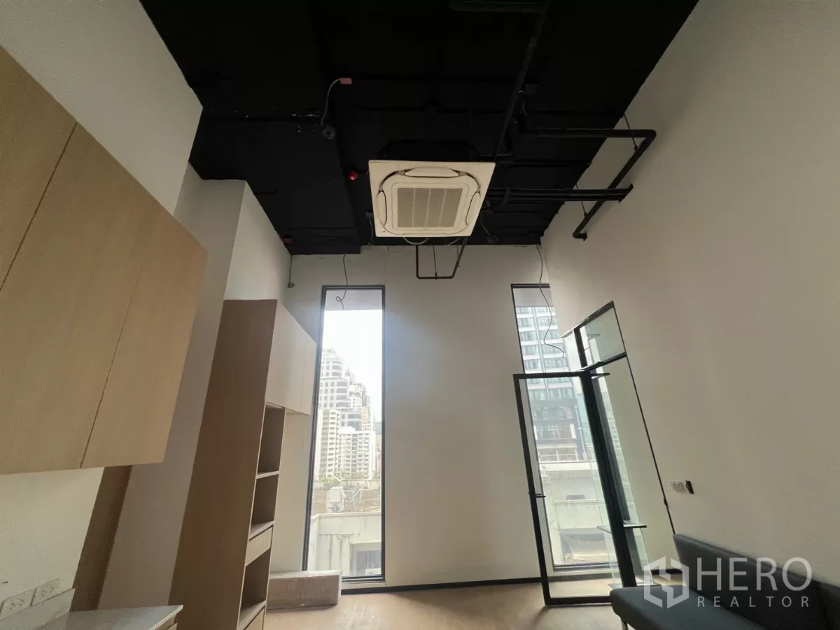 零售空间 出租 - 高挑层高的展厅，设有高窗、嵌入式空调、玻璃门与木质柜体。