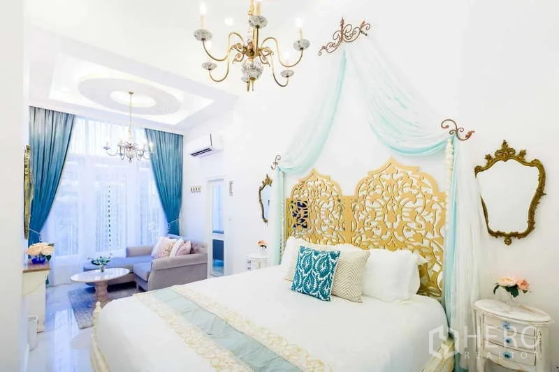 联排别墅 出租在Lat Phrao, Bangkok - 主卧配金色雕花床头、纱幔吊顶、水晶吊灯及窗边会客区