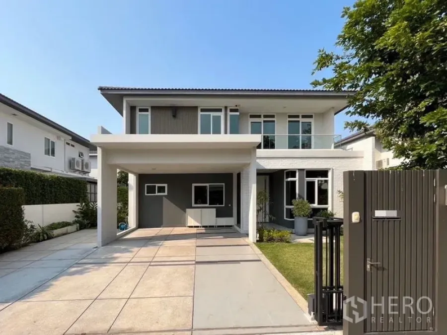 Detached House for rent in Samut Prakan - Contemporary two-storey detached house exterior with covered carport, gated driveway and front lawn.