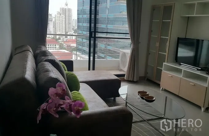 Condominium for rent in Watthana, Bangkok - Cozy sofa lounge facing a TV with large sliding glass and skyline views.