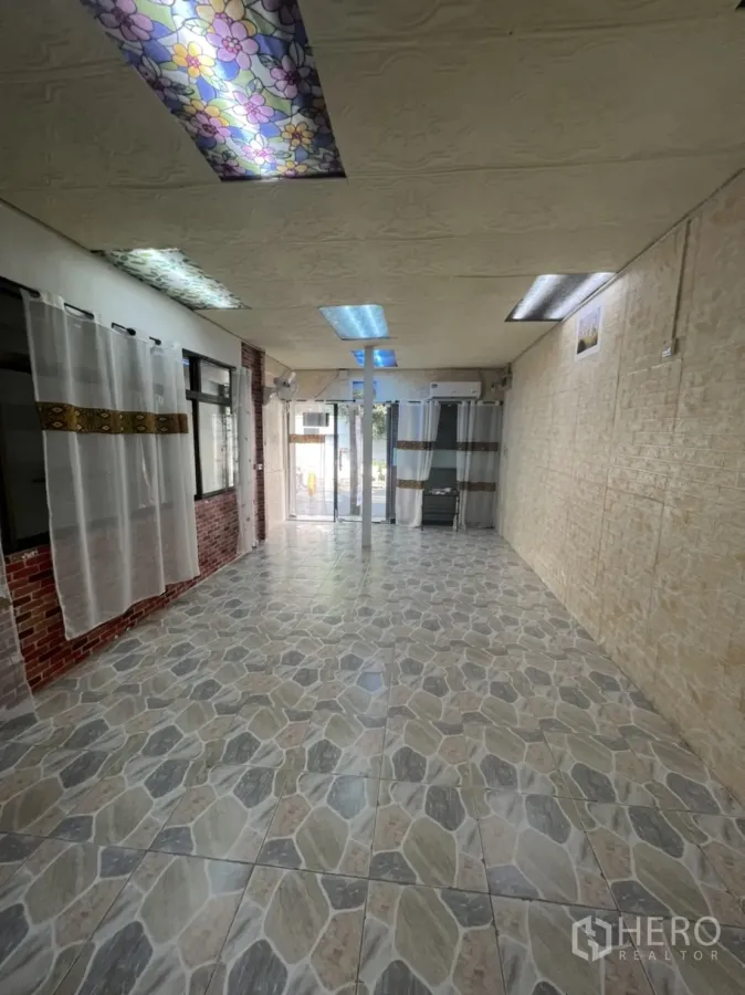 零售空间 出租在Watthana, Bangkok - 开放式店内，石纹地砖、玻璃门、砖纹点缀墙与日光灯照明。