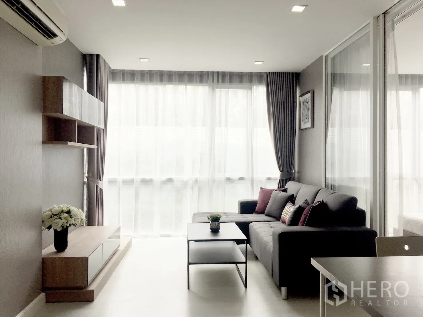 คอนโด ขายในPhra Khanong, Bangkok - ห้องนั่งเล่นสว่าง หน้าต่างสูงจรดเพดาน โซฟาเข้ามุม ชั้นวางบิวท์อิน และโต๊ะกลาง