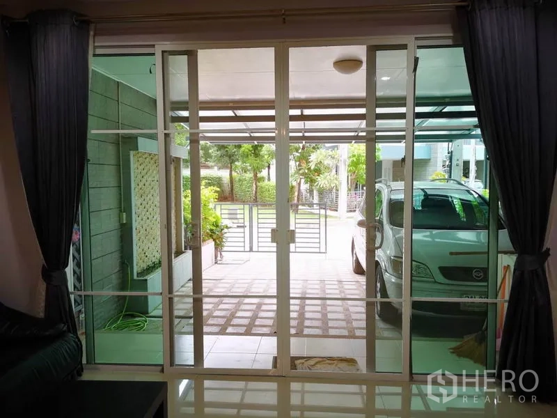 Townhouse for rent in Suan Luang, Bangkok - View from living room through sliding glass doors to the covered carport and front gate.