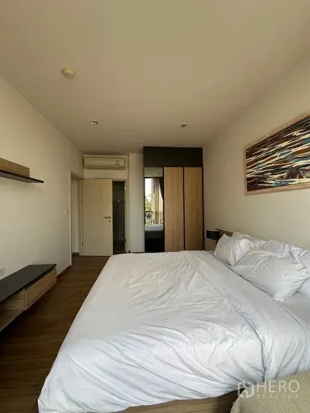 公寓 出租在Watthana, Bangkok - 主卧朝衣柜和房门的视角，木地板与空调