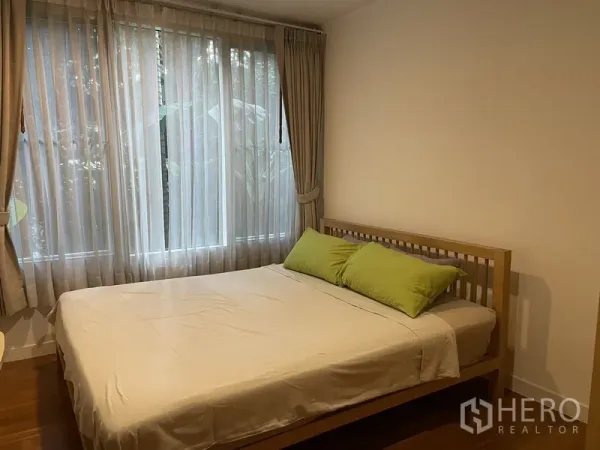 Condominium for rent in Pathum Wan, Bangkok - Cozy bedroom with double bed, sheer curtains and a large window overlooking garden greenery.