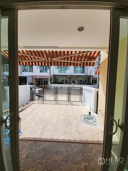 Townhouse for rent in Wang Thonglang, Bangkok - View from inside to the front terrace and gated carport with striped awning.