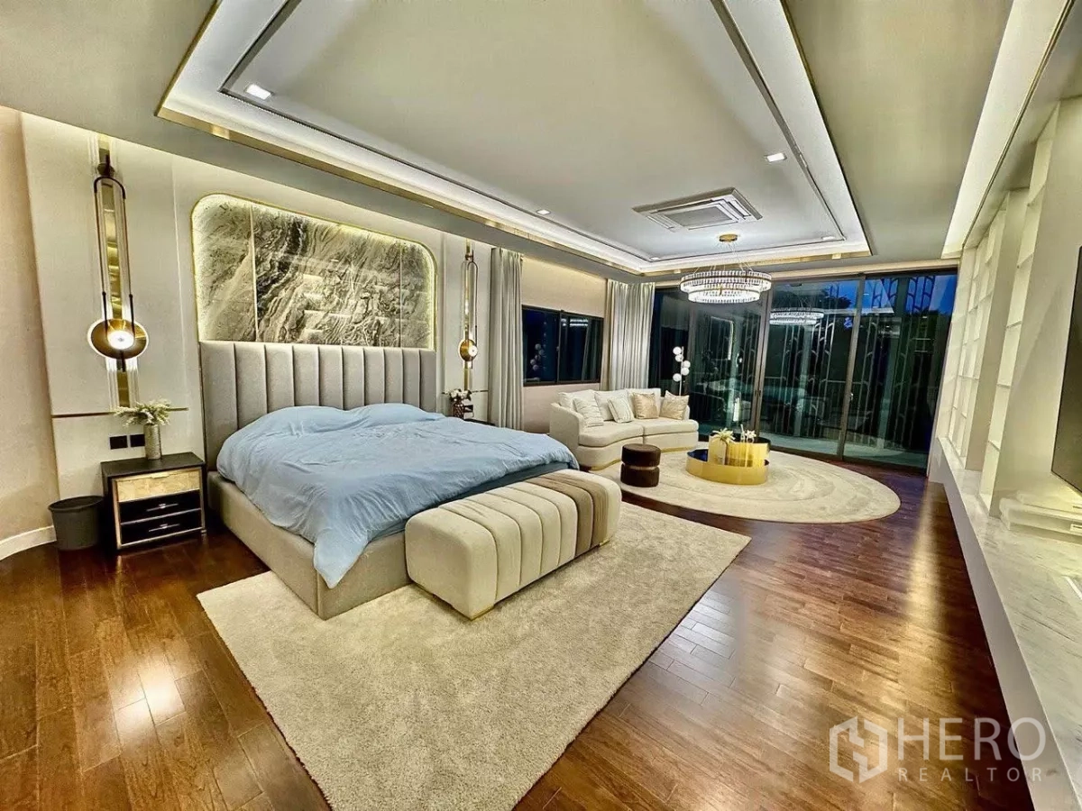 Detached House for sale in Saphan Sung, Bangkok - Expansive master bedroom with seating area, wood floors and access to a balcony.