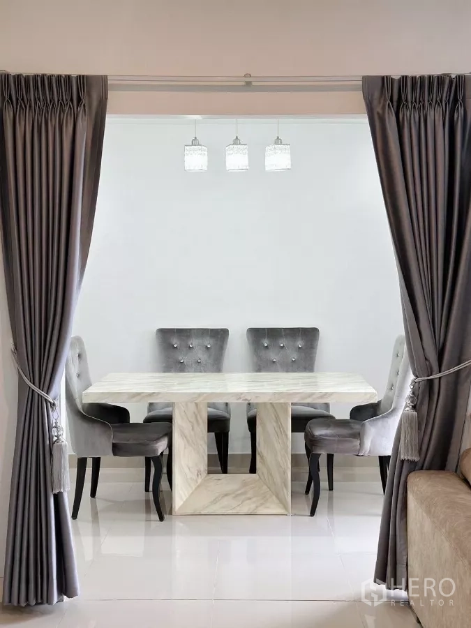 Townhouse for rent in Bang Phli, Samut Prakan - Dining area with a marble table and upholstered chairs framed by full-length drapes.