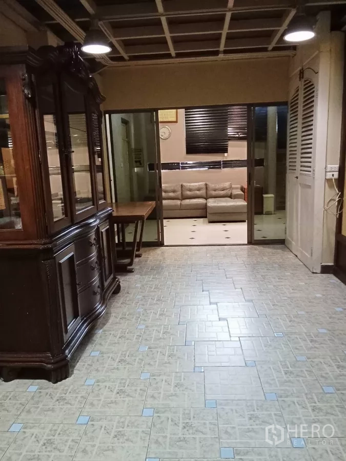 สำนักงานที่บ้าน ให้เช่าในLat Phrao, Bangkok - โถงทางเดินพร้อมตู้ไม้คลาสสิก มองเห็นห้องนั่งเล่นผ่านประตูกระจกบานเลื่อน