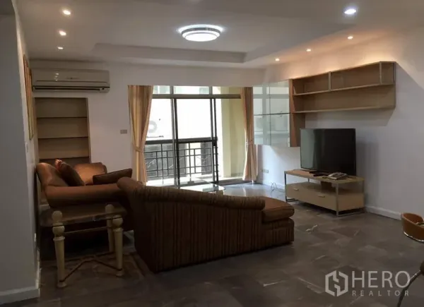 คอนโด ให้เช่าหรือขายในWatthana, Bangkok - ห้องนั่งเล่นกว้าง โซฟา L‑shape ชั้นวางทีวีและชั้นบิวท์อิน พร้อมประตูกระจกสไลด์ออกสู่ระเบียง