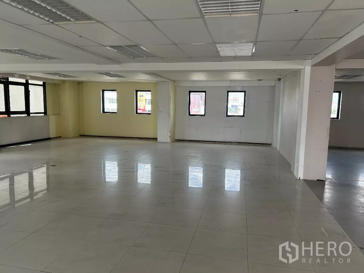 办公空间 出租在Din Daeng, Bangkok - 大型开放工作区，浅色瓷砖地、格栅灯和多扇窗户。