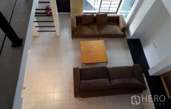 Townhouse for sale in Khlong Toei, Bangkok - Top-down view of tiled living room with two sofas, coffee table and large windows for natural light.