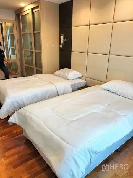 Condominium for rent in Watthana, Bangkok - Second bedroom with twin single beds and upholstered wall panels on timber flooring.