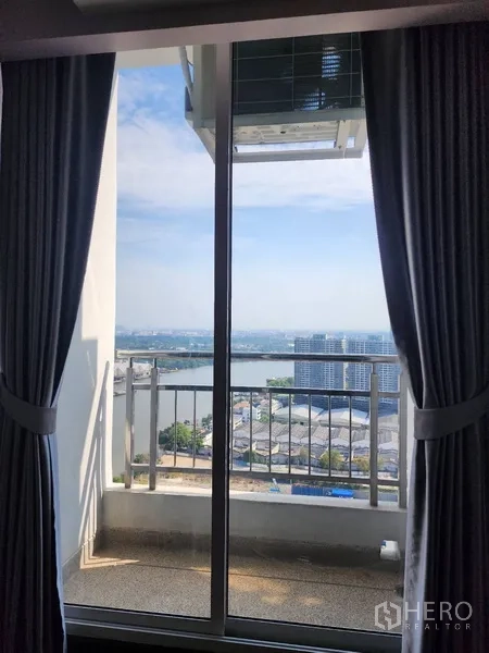 公寓 出租在Yan Nawa, Bangkok - 窗帘框住的推拉门，通往小阳台，远眺河景与城市