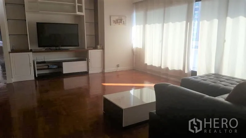 Condominium for rent in Watthana, Bangkok - Bright living room with L-shaped sofa, low coffee table and sheer curtains filtering sunlight.
