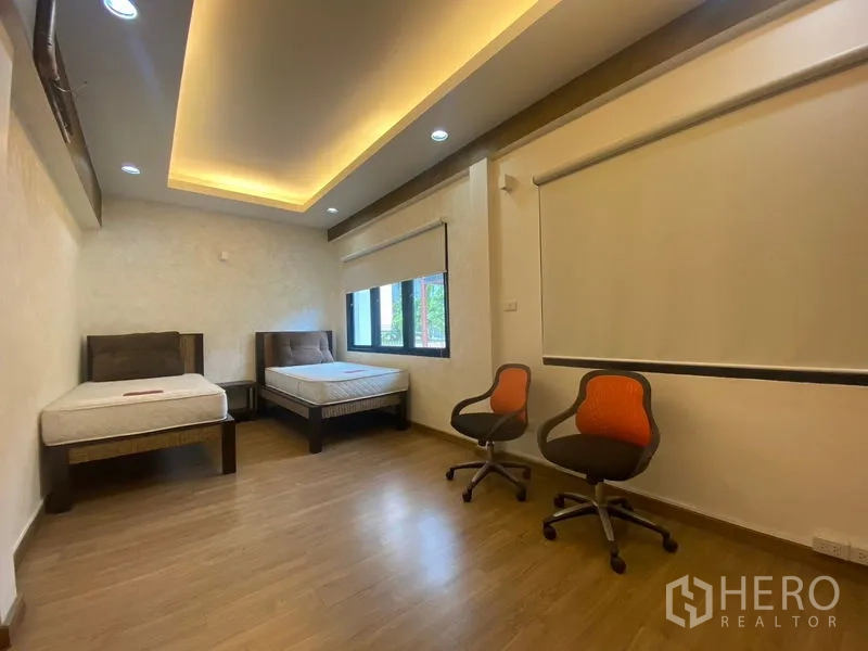 Detached House for sale in Khlong Toei, Bangkok - Large secondary bedroom with twin beds, wooden floors, and recessed lighting.