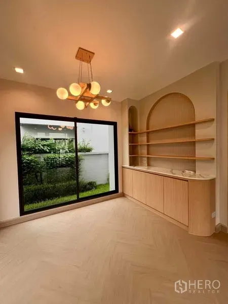 บ้าน ขายในBang Kruai, Nonthaburi - มุมชั้นวางบิลท์อินไม้พร้อมโคมไฟแขวน และประตูกระจกเปิดสู่สวนส่วนตัว