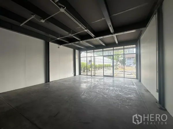 零售空间 出租 - 开放式室内空间，水泥地面，整面落地窗与外露梁架天花。