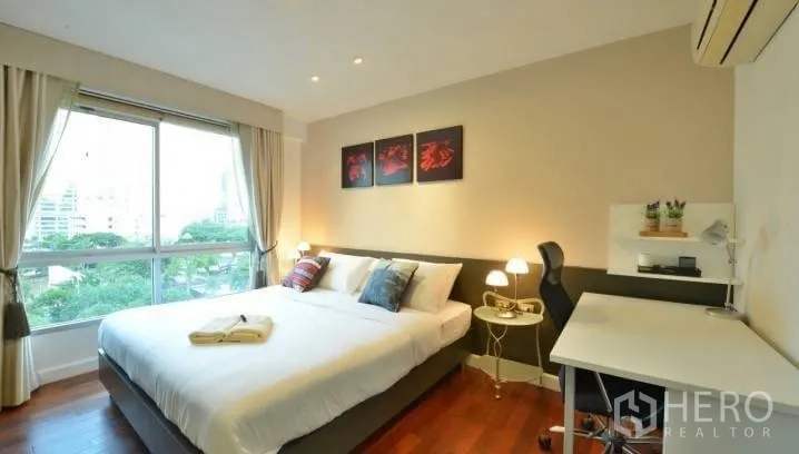 Condominium for rent in Watthana, Bangkok - Cozy bedroom angle showing artwork above the bed, bedside lamps and a built-in study desk by the window.